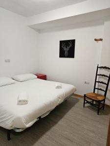 1 dormitorio con 1 cama blanca y 1 silla en Agradable apartamento familiar en Sierra Nevada