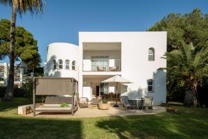 uma casa branca com um quintal com cadeiras e mesas em Melia Cala d'Or Boutique Hotel em Cala d´Or
