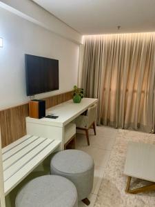 a room with a desk with a television and two chairs at INOVA FLAT conforto no Condominio Cosmopolitan in Palmas