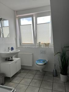 La salle de bains est pourvue de toilettes, d'un lavabo et de 2 fenêtres. dans l'établissement Messezimmer nahe Flughafen direkte Verbindung Messe, à Langenhagen