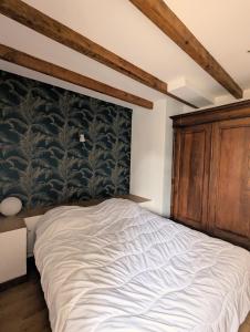1 dormitorio con 1 cama grande y cabecero de madera en Maison de ville à 5mn de la plage-jardin clos proche plage en Planguenoual