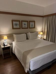 a bedroom with a large white bed and two lamps at Gaben Hotel in Jaú