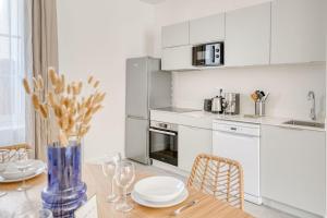 Una cocina con gabinetes blancos y una mesa con sillas. en Appartement Aigrette - La Maison Heureuse - Welkeys, en Saint-Georges-dʼOléron
