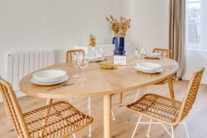 una mesa de madera con sillas, platos y copas de vino en Appartement Aigrette - La Maison Heureuse - Welkeys, en Saint-Georges-dʼOléron