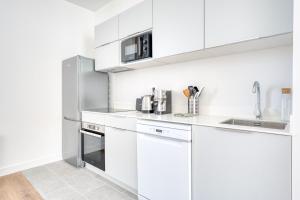 Una cocina con gabinetes blancos y un refrigerador de acero inoxidable. en Appartement Aigrette - La Maison Heureuse - Welkeys, en Saint-Georges-dʼOléron 8 fotos más