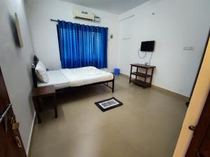 een kleine kamer met een bed en een televisie bij Maria Comfort Stay in Calangute