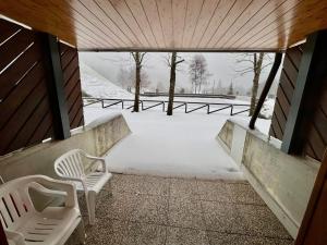 two white chairs sitting on a porch in the snow at Tormentina - Piancavallo in Piancavallo