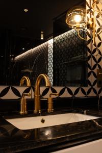 a bathroom sink with gold faucets and a mirror at Mandarin Club House in Batumi