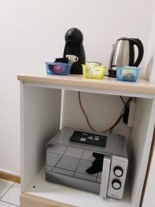 Un microondas debajo de un estante con una cafetera encima. en PERFECT APARTMENT for centre and Miramare, en Trieste