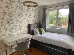 a bedroom with a bed and a desk and a window at 2 Bed House in Hampton - Free parking in Hanworth