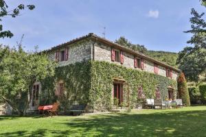 a building covered in ivy with tables and chairs in a yard at Villa Casanova by Mmega in Cerbaiolo