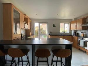 a kitchen with a large island with four bar stools at 2 Bed House in Hampton - Free parking in Hanworth