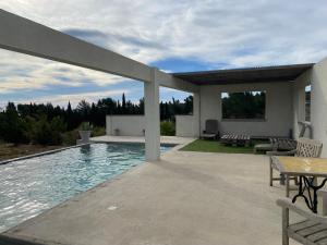 a swimming pool with a table and a patio at Le Carignan in Peyriac-de-Mer
