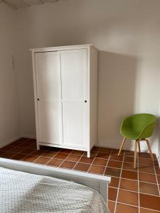 Müllernhof في Faßberg: غرفة نوم مع خزانة بيضاء وكرسي أخضر