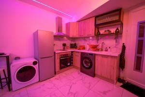 a kitchen with pink lights in a kitchen at L'Elixir d'Amour Love Room proche Disneyland in Étampes-sur-Marne