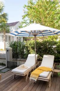 zwei Stühle und ein Sonnenschirm auf einer Terrasse in der Unterkunft Green Cottage at Casa Zoe in Charleston