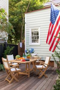 eine Terrasse mit Tisch und Stühlen und einer amerikanischen Flagge in der Unterkunft Green Cottage at Casa Zoe in Charleston