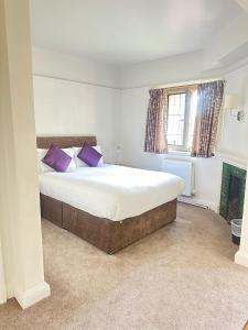 Westminster College في كامبريدج: غرفة نوم مع سرير كبير مع وسائد أرجوانية