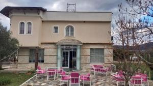 un edificio con tavoli e sedie rosa di fronte ad esso di Veal Hotel and Restaurant a Tepelenë