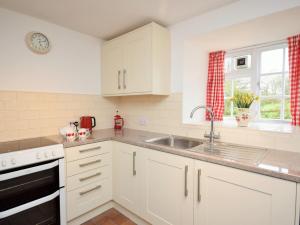 a kitchen with white cabinets and a sink and a window at 2 Bed in Aylesbeare THEDA in Aylesbeare