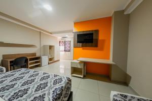 a bedroom with a bed and an orange wall at Hotel Yvera Cataratas in Puerto Iguazú