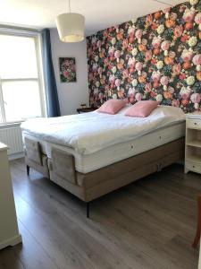 1 dormitorio con 1 cama grande y pared de flores en Our home, your home, close to Amsterdam en Nederhorst den Berg