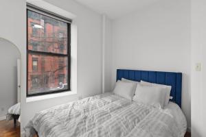 a bedroom with a bed with a blue headboard and a window at 89-3FS Newly Furnished 2br 1bath UES in New York