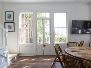 a dining room with a table and two windows at The Aviary at CasaZoe in Charleston