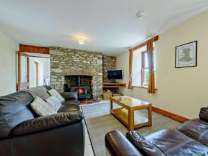a living room with a leather couch and a stone fireplace at 3 Bed in New Quay LLWYD in Pencader