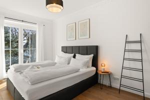 a bedroom with a bed with white sheets and a ladder at YUVA HOMES am Kurpark in Bad Wörishofen