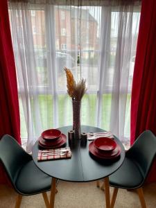 a table with red plates and a vase on it in front of a window at 2bdroom city center luxury House in Birmingham