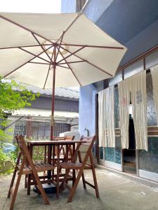 a table and chairs with an umbrella on a patio at Blue House in Beppu
