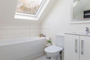 a white bathroom with a toilet and a window at Serene Riverside: 6BR Luxury Retreat in Curdridge in Curdridge