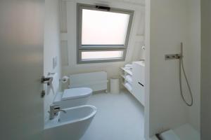 a white bathroom with two toilets and a window at Milan Design Suites in Milan