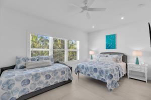 a white bedroom with two beds and a window at Peaceful Palms A2 in Islamorada