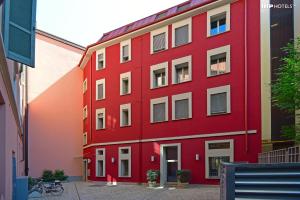 a red building with white windows on a street at Milan Design Suites in Milan