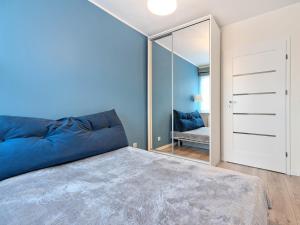 a bedroom with a blue bed and a mirror at Platinium Zaspa - Pilotów 14 in Gdańsk