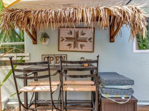 een patio met 2 stoelen, een tafel en een rieten dak bij Luxury Couples Villa with private pool in Largo