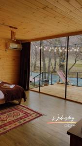 Lightwood cabins في Kʼareli: غرفة نوم بسرير ونافذة زجاجية كبيرة