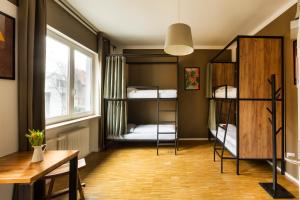 a dorm room with bunk beds and a table and a desk at Five Reasons Hostel & Hotel in Nürnberg