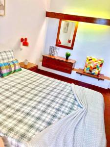 een slaapkamer met een bed met een geruite deken en een spiegel bij Resort Albufeira T1, Praia da Oura in Albufeira
