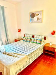 een slaapkamer met een bed en twee tafels en een schilderij bij Resort Albufeira T1, Praia da Oura in Albufeira
