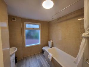 a bathroom with a tub and a toilet and a window at Central 5BR Retreat - Walk to Tube, Explore London in London