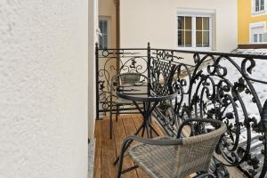 a wrought iron railing with two chairs and a table on a balcony at YUVA HOMES am Kurpark in Bad Wörishofen