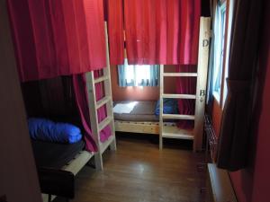 軽井沢町にあるベルキャビン ゲストハウスの二段ベッド2台と赤いカーテンが備わる客室です。