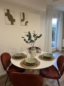 une table avec des chaises, des assiettes et un vase sur elle dans l'établissement Hana Home T2 Guyancourt, à Guyancourt