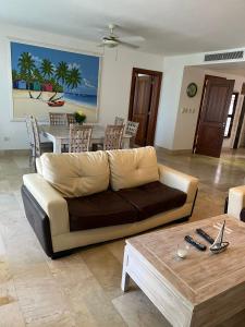 ein Wohnzimmer mit einem Sofa und einem Tisch in der Unterkunft Bello y cómodo apartamento, frente al mar in Punta Cana