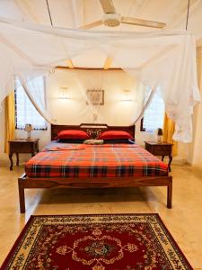 een slaapkamer met een hemelbed en een tapijt bij Giant House Malindi in Malindi