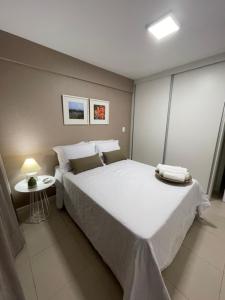 Un dormitorio con una gran cama blanca y una mesa en Novo quarto e sala - J. Armação - Vista Mar!, en Salvador