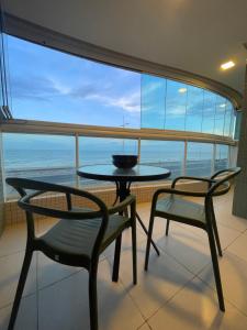 1 mesa y 2 sillas en una habitación con ventana grande en Novo quarto e sala - J. Armação - Vista Mar! en Salvador
